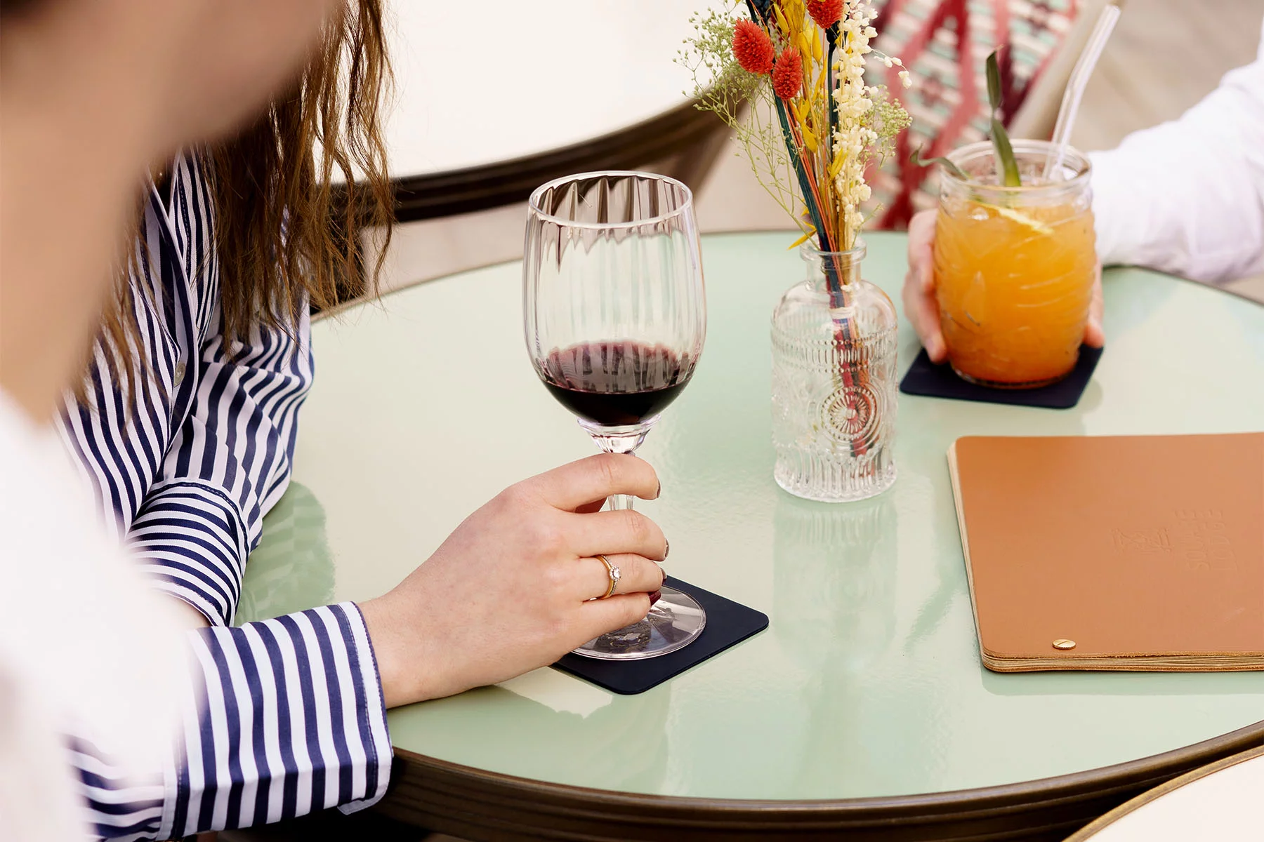 Personnes sur le patio végétalisé autour d'une table, tenant un verre de vin à la main et un cocktail, profitant de l'ambiance conviviale d'Andina.
