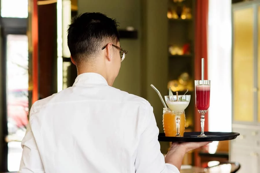 Serveur du restaurant Andina à La Roche-sur-Yon de dos, portant et servant des cocktails de la carte avec professionnalisme.