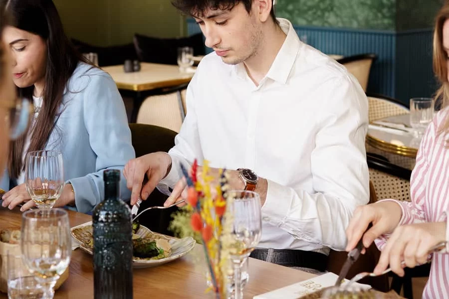 Jeune femme et homme dégustant des plats à la carte au restaurant Andina à La Roche-sur-Yon, entourés de leurs proches autour d'une table conviviale.