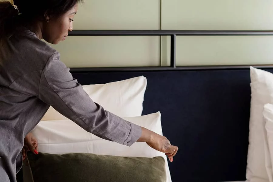 Femme de chambre en train de remettre le lit dans une chambre de l'Hôtel Square Lodge à La Roche-sur-Yon.
