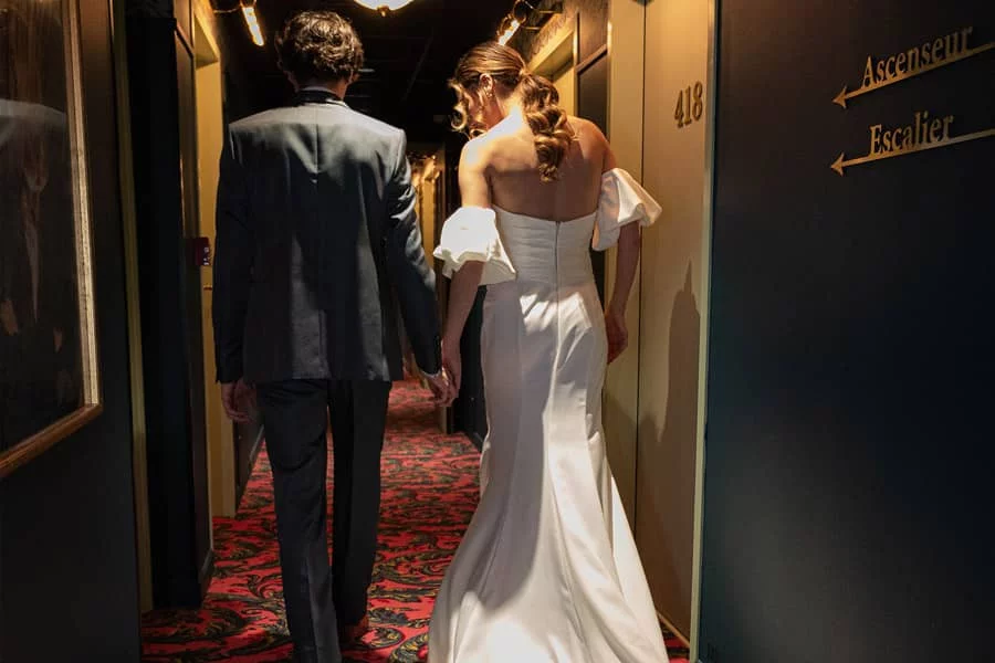 Des mariés posant de dos dans le couloir de l'hôtel Square Lodge à La Roche-sur-Yon, créant un moment élégant et romantique.