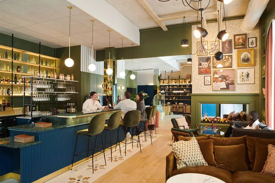 Bar du restaurant Andina à La Roche-sur-Yon, deux clients assis au comptoir, proche de l'espace cheminée, profitant du moment, tandis que le barman leur propose un vin.