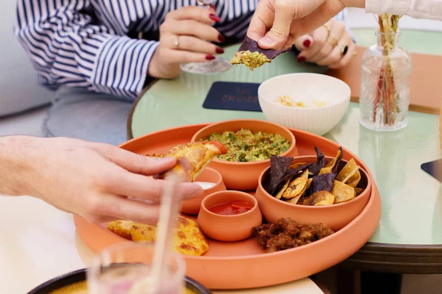 Zoom sur une planche Para Picar avec des mains qui picorent dedans, restaurant Andina à La Roche-sur-Yon.